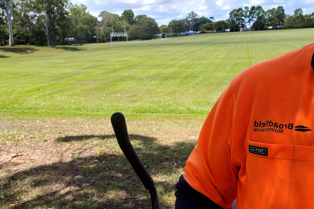 Operator mowing a large open field with a wide-deck mower